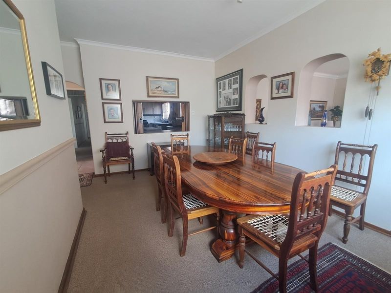 A traditional dining room featuring a serving hatch to the kitchen, decorative archway niches, and carpeted flooring.