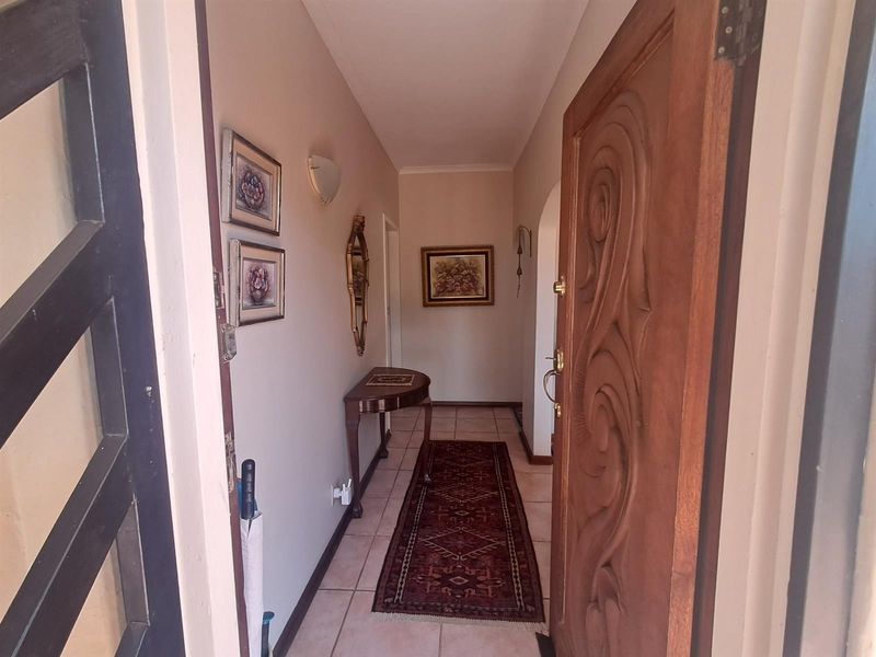 Entrance hallway featuring a decorative carved wooden front door and ceramic tiled flooring leading into the home.