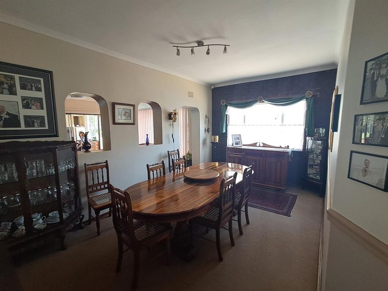 A traditional dining room featuring an exposed brick wall, arched interior openings, and carpeted flooring, providing a classic and functional space for meals.