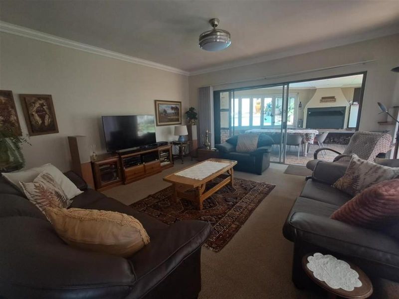 Spacious open-plan living area featuring carpeted flooring, ceiling fan, and large sliding glass doors providing seamless access to the outdoor patio space.
