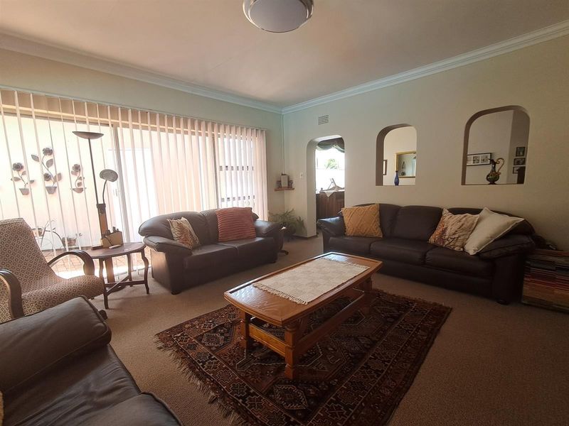 Spacious living room featuring neutral walls, coving, and large sliding glass doors with vertical blinds, providing access to the outdoor area.