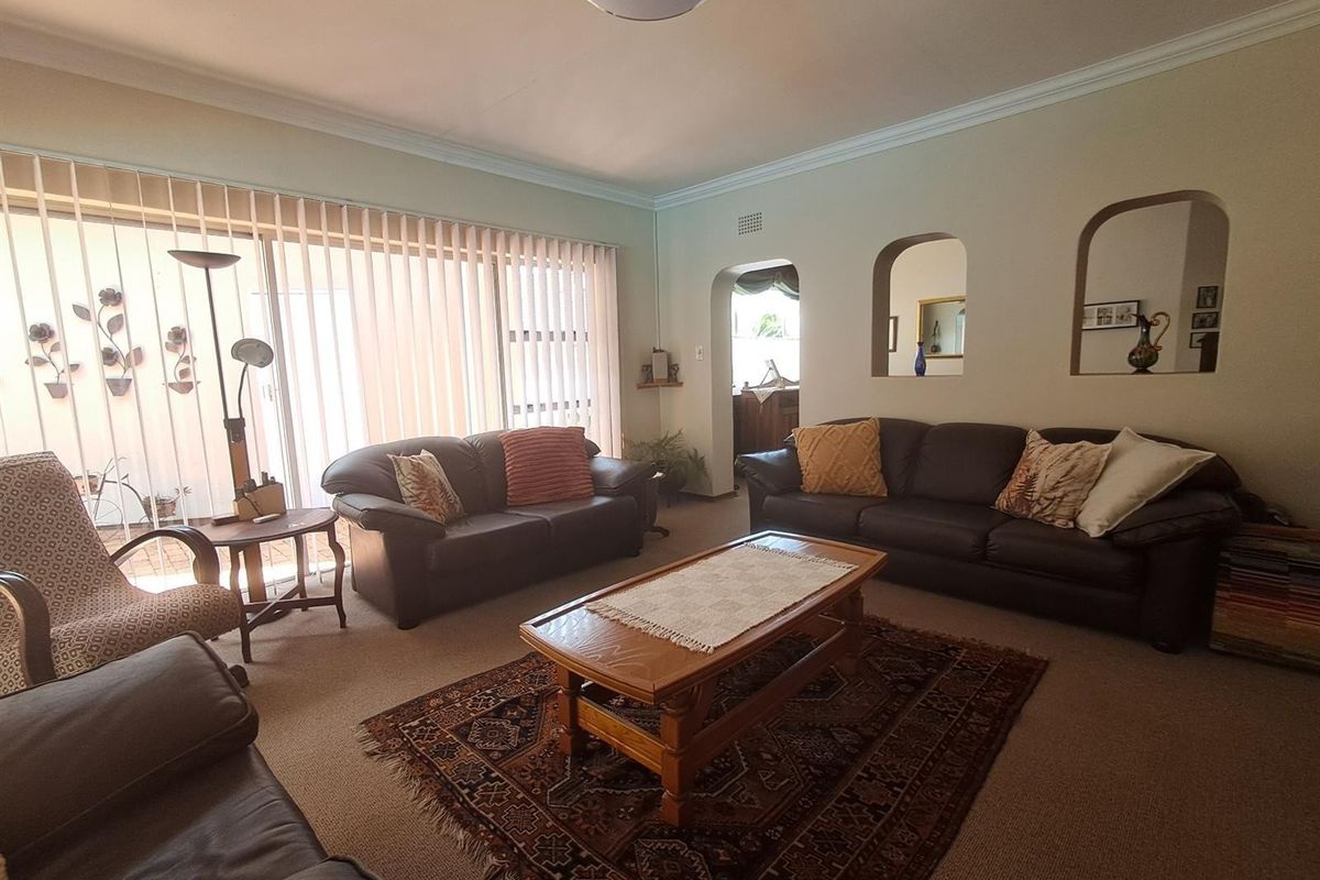 Spacious living room featuring neutral walls, coving, and large sliding glass doors with vertical blinds, providing access to the outdoor area.