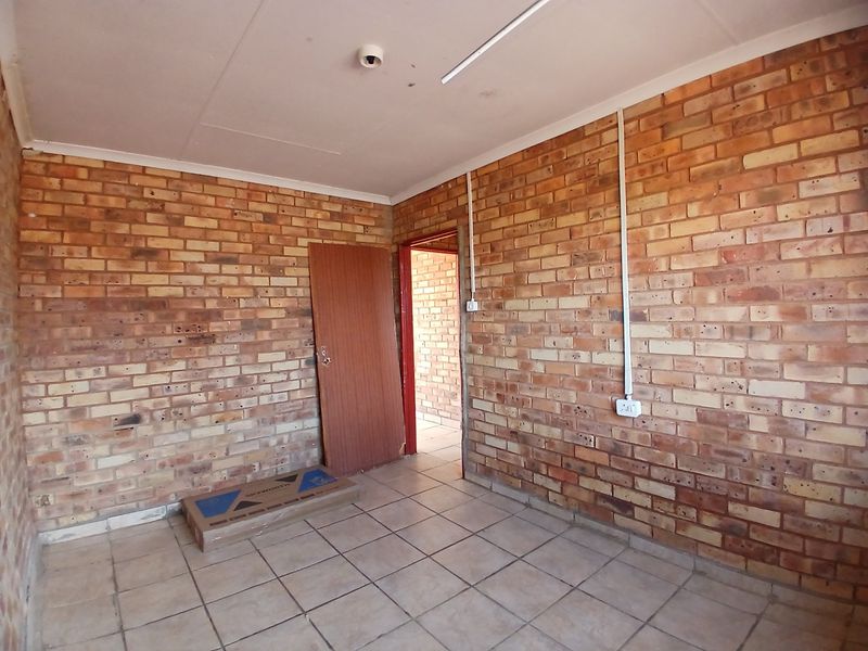 An empty bedroom featuring exposed brick walls, ceramic tiled flooring, and surface-mounted electrical conduits.