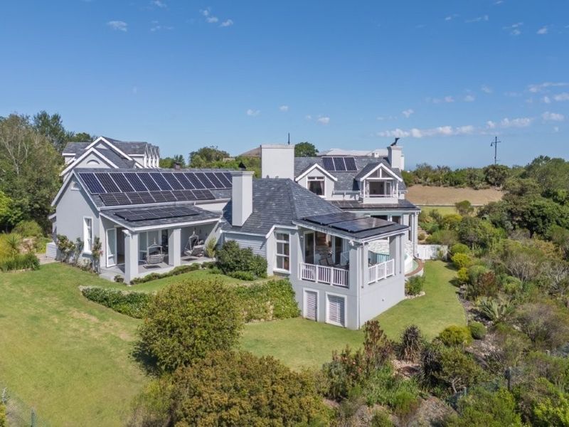 Aerial view of a large residential property featuring a slate roof, extensive solar panel installation, and well-maintained landscaped gardens with covered patio areas.