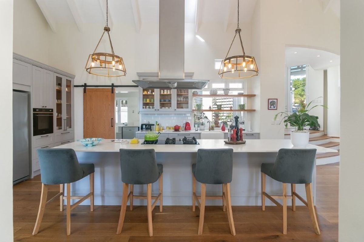 Modern farmhouse-style kitchen featuring a large central island, high vaulted ceilings, shaker cabinetry, and premium built-in appliances with warm timber flooring.