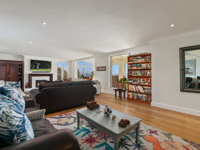 Spacious living room featuring hardwood flooring, recessed lighting, crown molding, and a fireplace, with large windows providing natural light and views.