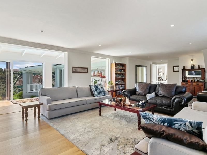 Spacious living room featuring hardwood flooring, recessed downlights, and large sliding glass doors that provide seamless access to the outdoor patio area.