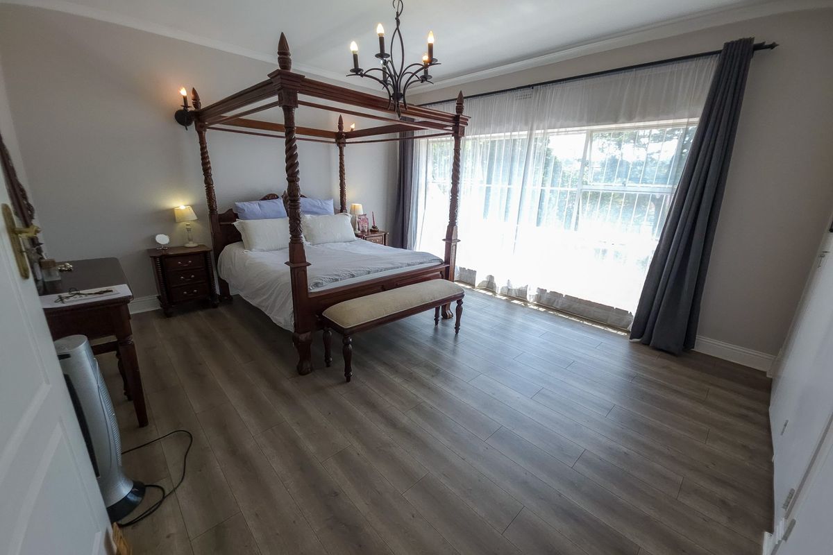 Spacious bedroom featuring modern laminate flooring, elegant cove cornicing, and a large window allowing for ample natural light.