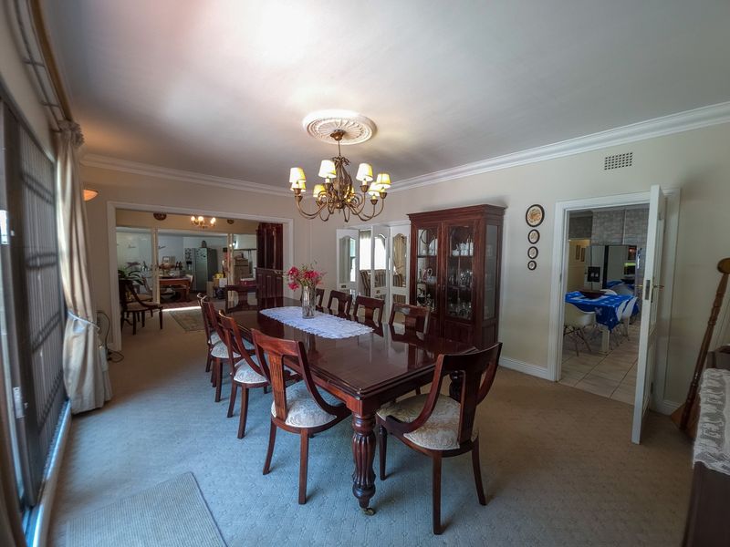 A traditional dining room featuring crown molding, a decorative ceiling rose, and access to adjacent living spaces.
