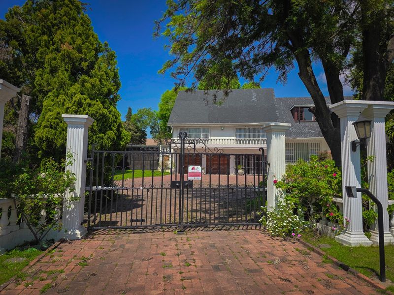 Front view of a double-story house featuring a wrought iron entrance gate, brick paved driveway, and a double garage.