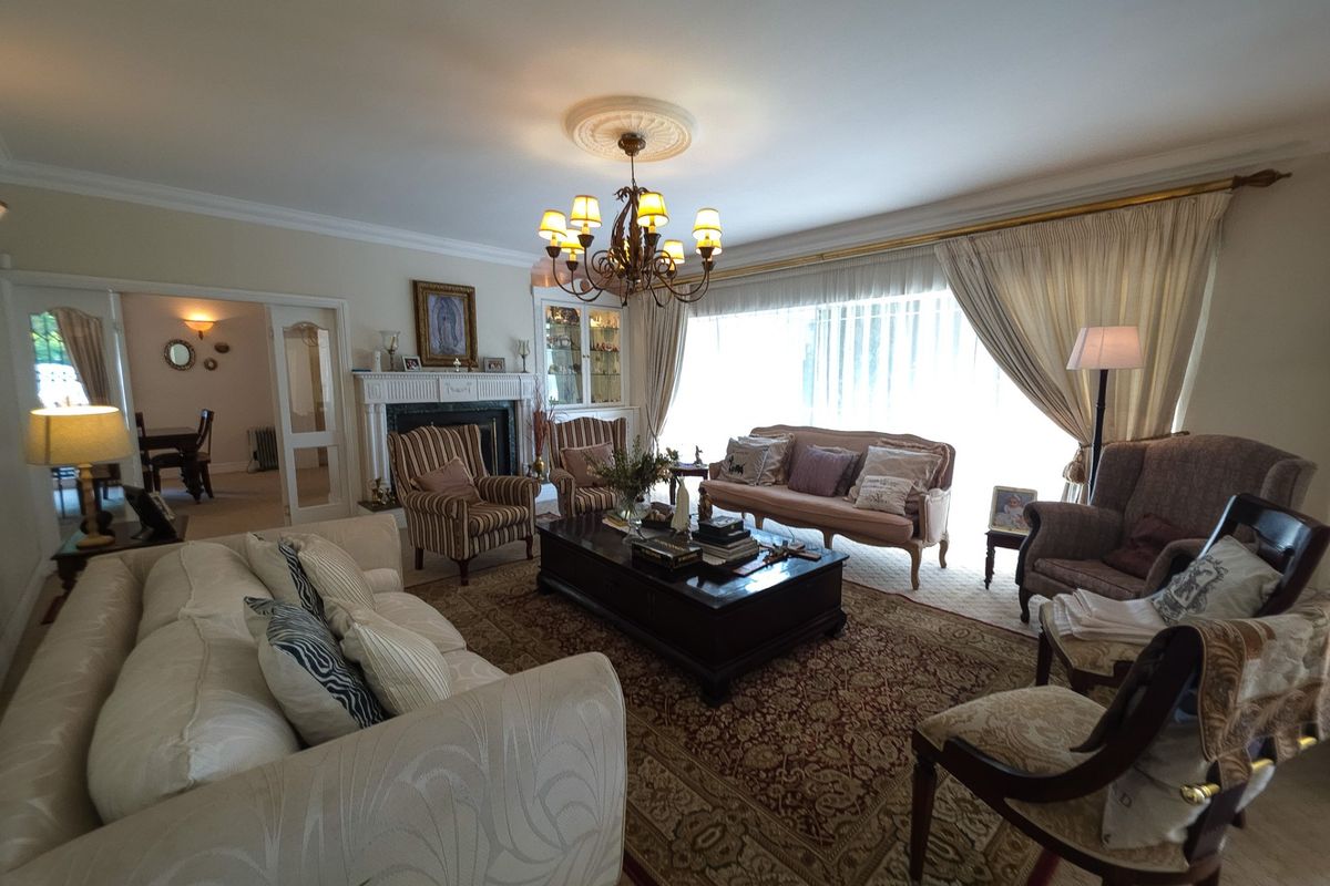 Spacious living room featuring a traditional fireplace with mantelpiece, decorative ceiling rose, coving, and a built-in display cabinet, offering a classic and comfortable atmosphere.