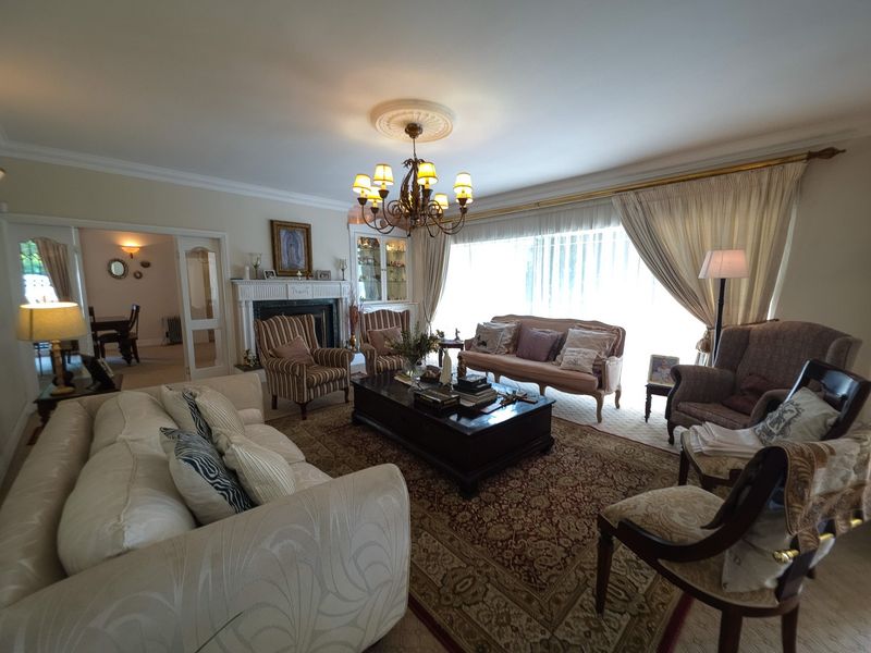 Spacious living room featuring a traditional fireplace with mantelpiece, decorative ceiling rose, coving, and a built-in display cabinet, offering a classic and comfortable atmosphere.