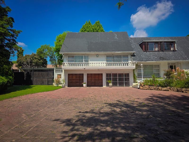 Front elevation of a double-story house featuring a paved driveway, double garage, and an upper-level balcony with security features.
