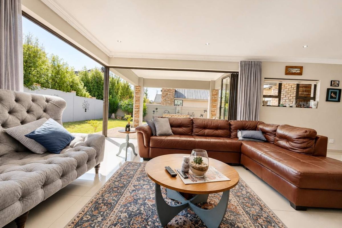 Spacious living room featuring large stacking glass doors that open onto a covered patio, creating a seamless indoor-outdoor flow with abundant natural light.