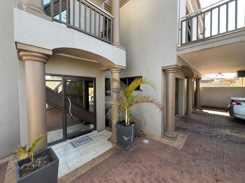 Front entrance area featuring a paved driveway, covered porch with decorative columns, and a glass entry door leading into the residence.