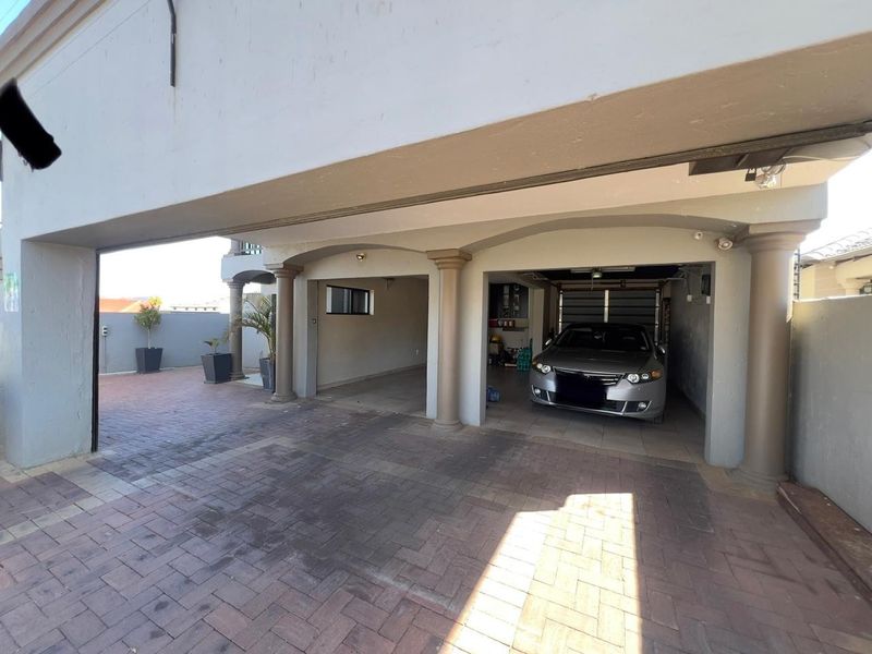 A spacious covered parking area featuring structural columns and paved flooring, providing secure off-street parking for multiple vehicles.