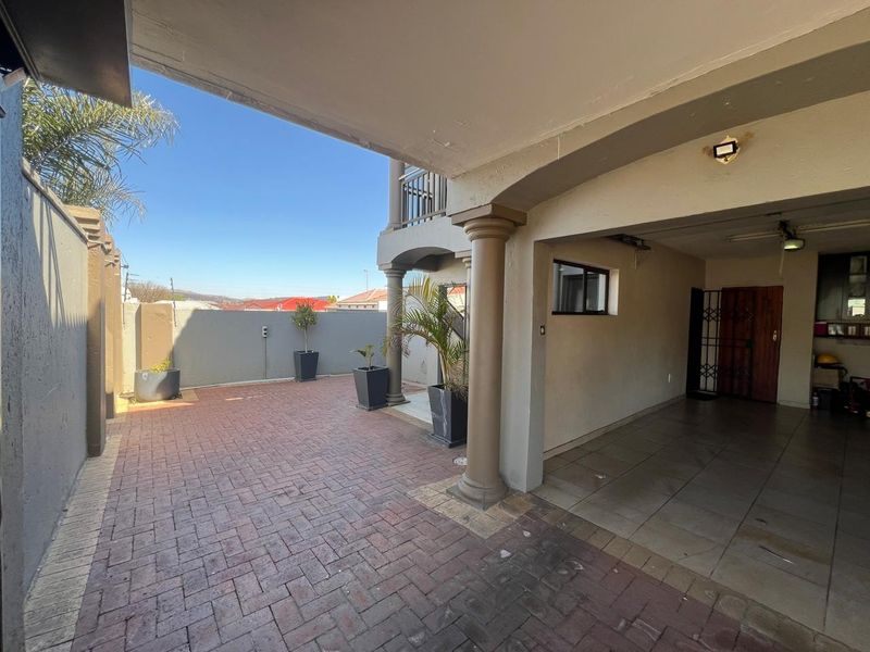 A covered patio area featuring brick paving, tiled flooring, and structural columns, providing a functional outdoor space for relaxation or entertainment.