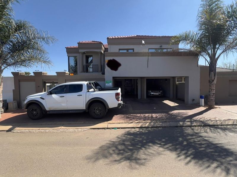 Front elevation of a double-story house featuring a double garage, paved driveway, and a small balcony.