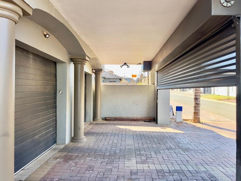 A covered garage area featuring paved flooring, decorative columns, and a roller shutter door, providing secure off-street parking.