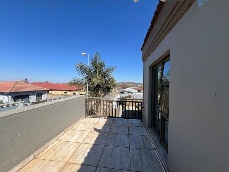 An elevated balcony featuring tiled flooring and a metal balustrade, offering clear views of the surrounding neighbourhood.