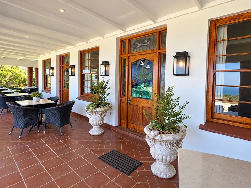 A spacious covered patio featuring terracotta tiling, timber-framed windows, and a decorative stained glass entrance door, offering a well-maintained outdoor living space.