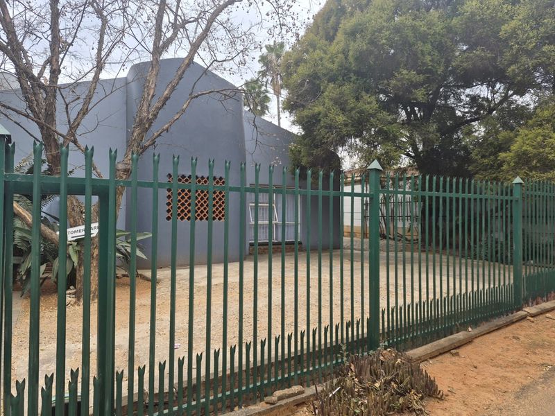 Front view of the property featuring a grey facade, decorative breeze block detailing, and secure steel palisade fencing along the street boundary.