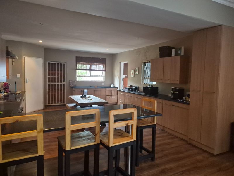 Open plan kitchen and living area featuring wood-look cabinetry, laminate flooring, and recessed lighting, offering a functional layout with potential for cosmetic updates.