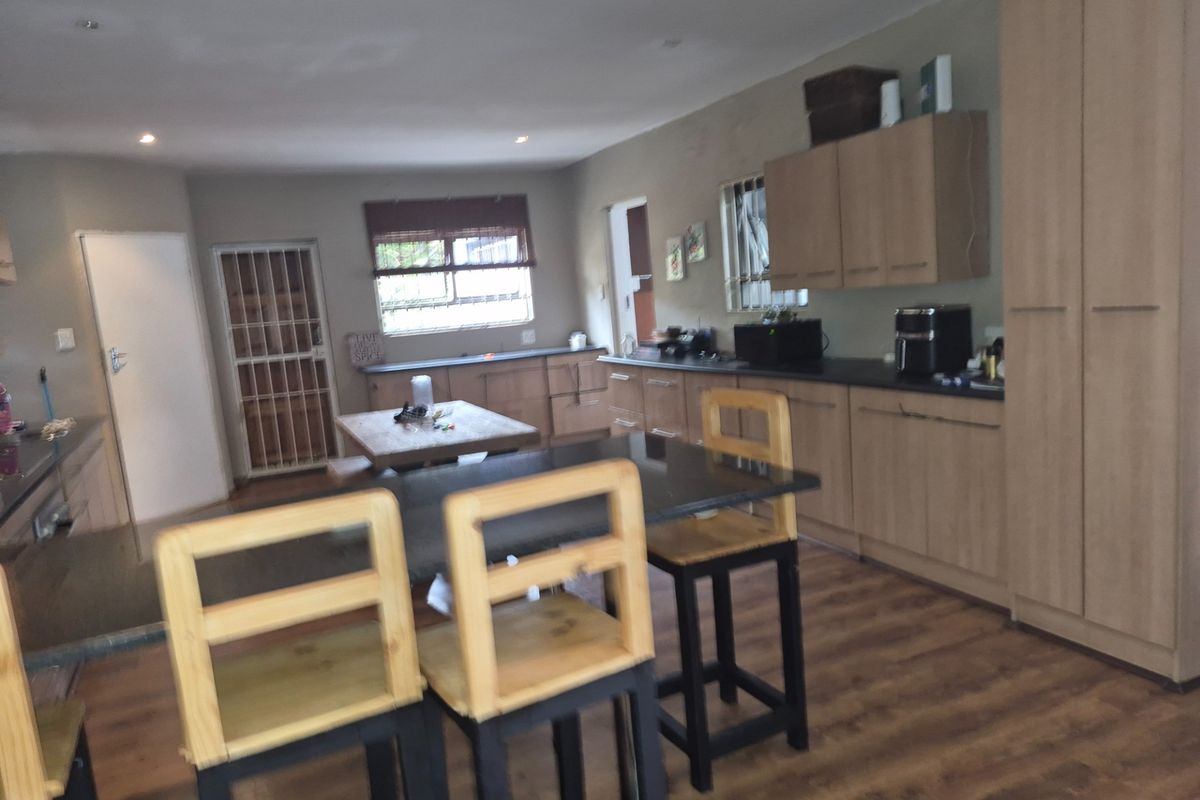 A functional kitchen featuring light wood cabinetry, dark laminate countertops, and laminate flooring, with an integrated breakfast bar area.