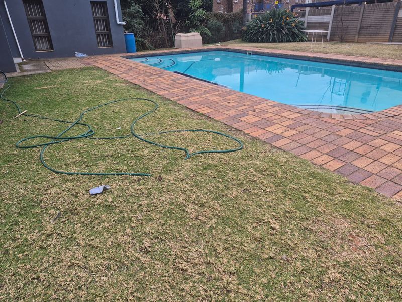Outdoor pool area featuring a swimming pool with brick coping and surrounding paved area, set within a private garden with boundary walling.