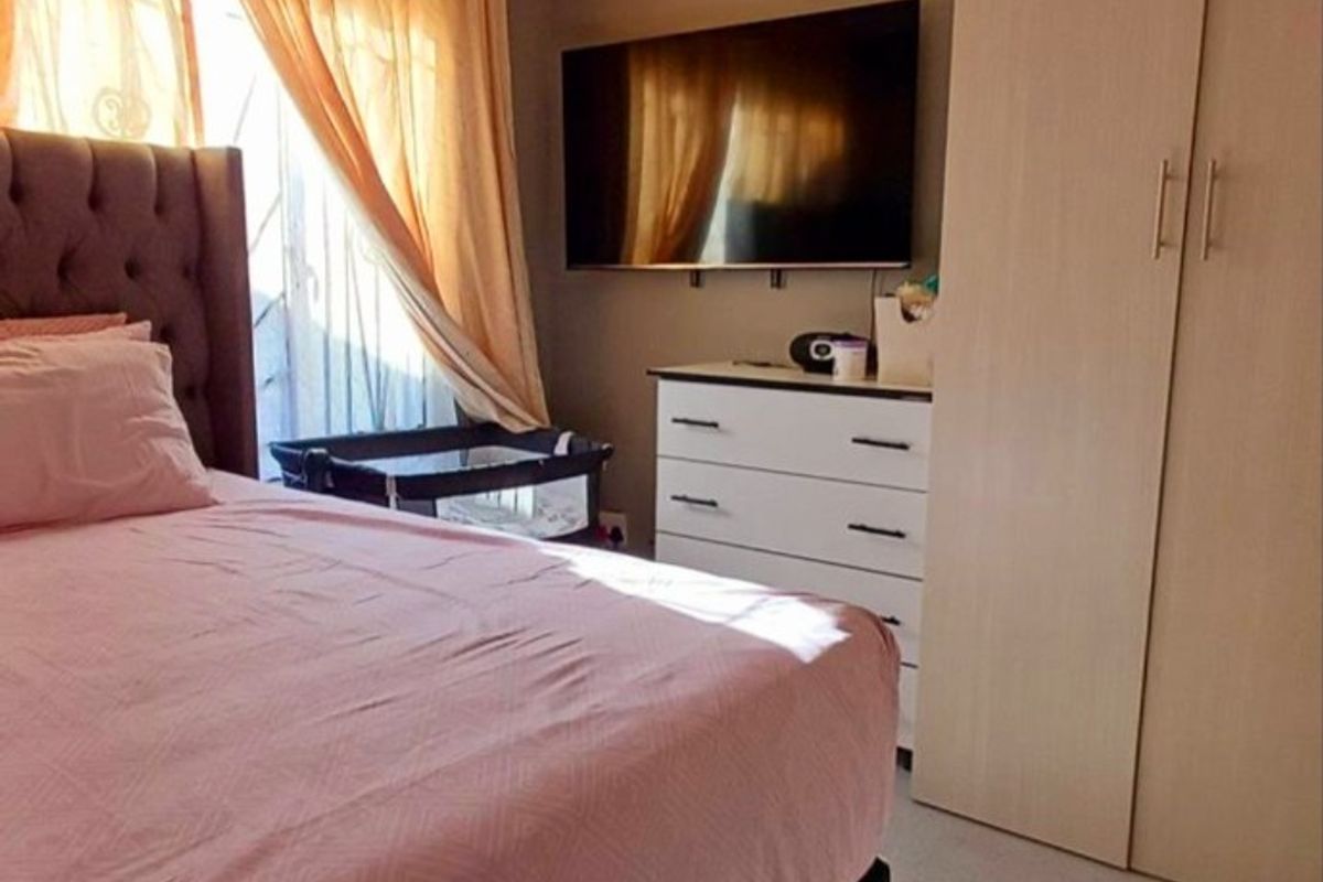 A functional bedroom featuring a built-in wardrobe and natural light through window treatments.