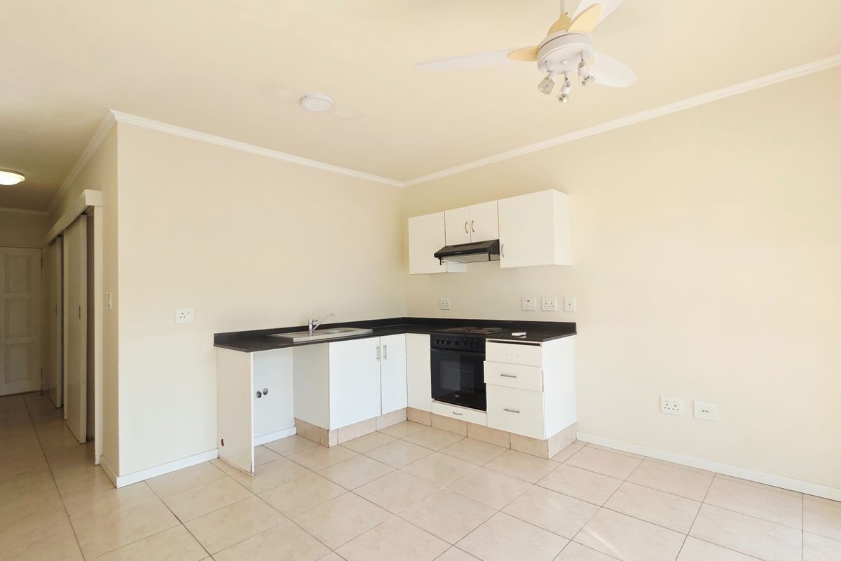A functional kitchen area featuring white cabinetry, a built-in oven with extractor fan, and tiled flooring, presenting a clean and ready-to-renovate space.