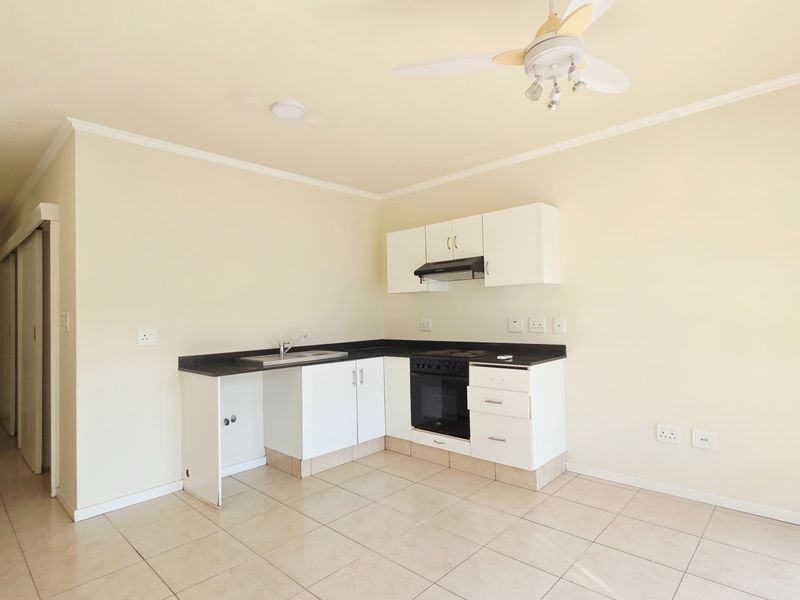 A functional kitchen area featuring white cabinetry, a built-in oven with extractor fan, and tiled flooring, presenting a clean and ready-to-renovate space.