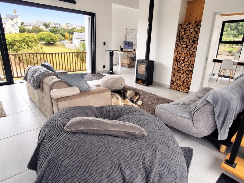 Modern open-plan living area featuring a sleek freestanding fireplace, integrated wood storage, and large sliding doors opening to an outdoor balcony.