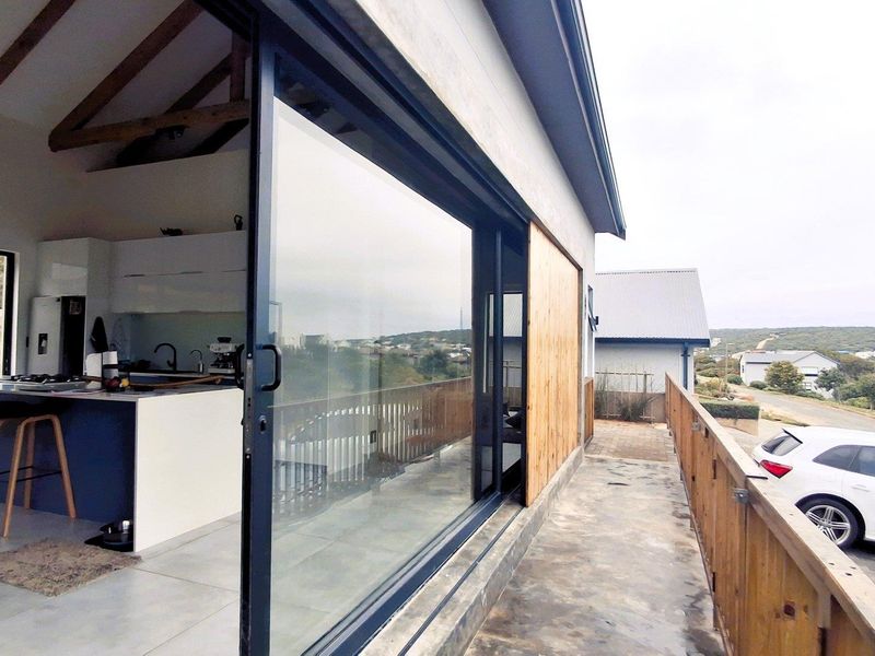 A modern balcony with wooden balustrades, offering a seamless transition to an open-plan kitchen area with exposed timber beams and contemporary finishes.