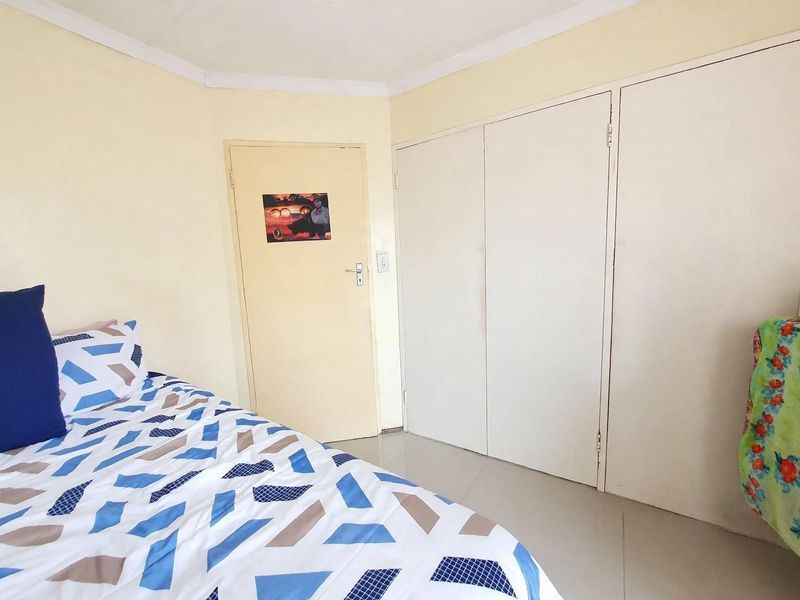 A bedroom featuring tiled flooring, coved ceilings, and built-in cupboards providing ample storage space.