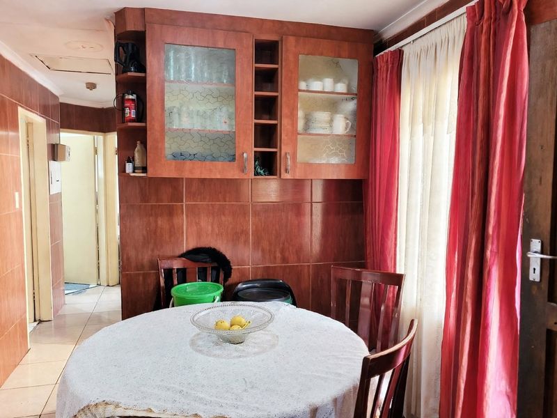 Dining area featuring built-in wooden cabinetry with glass-fronted display sections and tiled wall finishes, providing a functional space for meals.