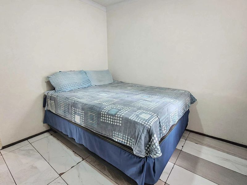 A simple bedroom featuring tiled flooring and neutral walls, providing a functional space ready for personal updates and cosmetic improvements.