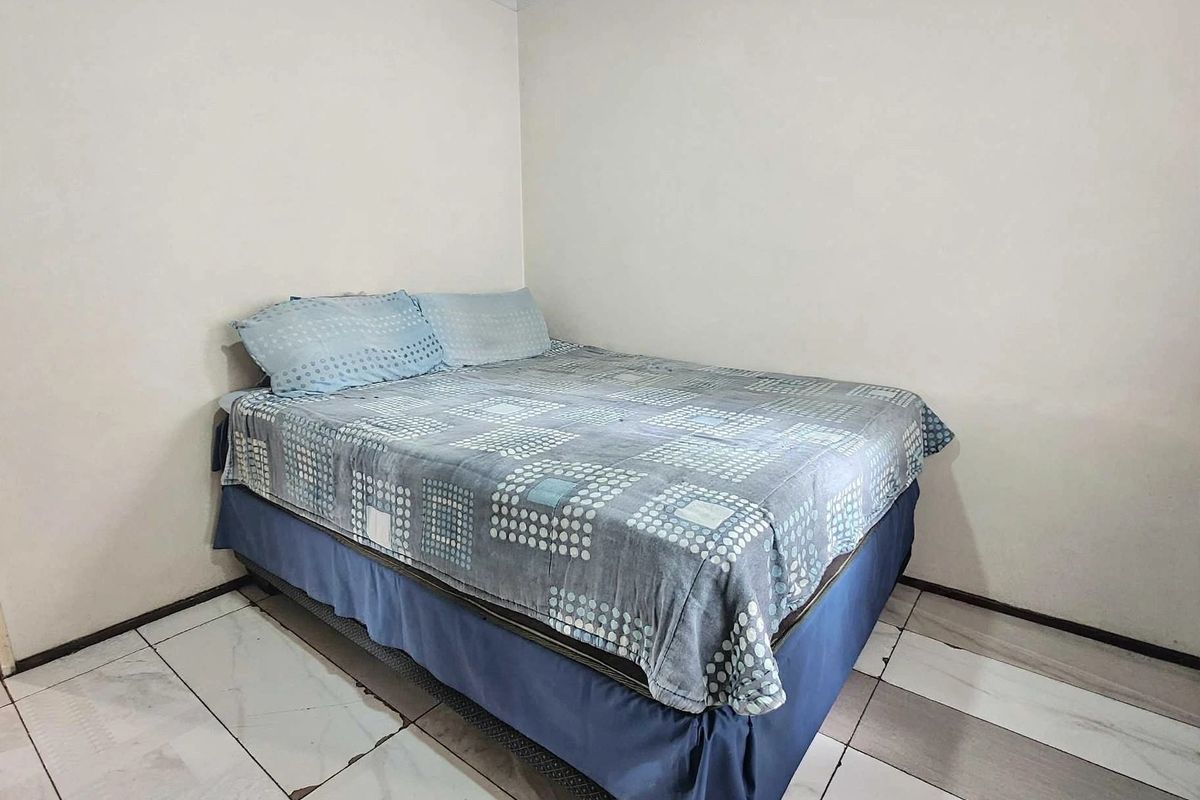 A simple bedroom featuring tiled flooring and neutral walls, providing a functional space ready for personal updates and cosmetic improvements.