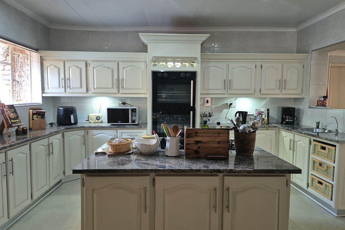 A well-maintained kitchen featuring cream-colored cabinetry, granite countertops, a central island, and integrated oven with under-cabinet lighting.