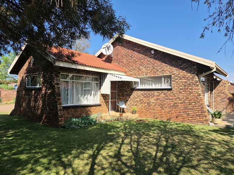 A well-maintained face-brick house featuring a tiled roof, security bars on windows, and a small covered entrance area set within a neat garden.