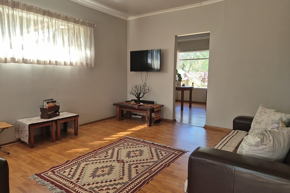 A comfortable living room featuring laminate flooring, neutral wall tones, and a coved ceiling, with a doorway leading to an adjacent room.