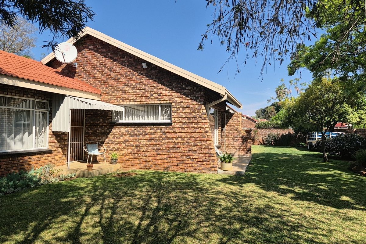 A view of the rear exterior of the house featuring a face brick facade, tiled roof, and a well-maintained garden area.
