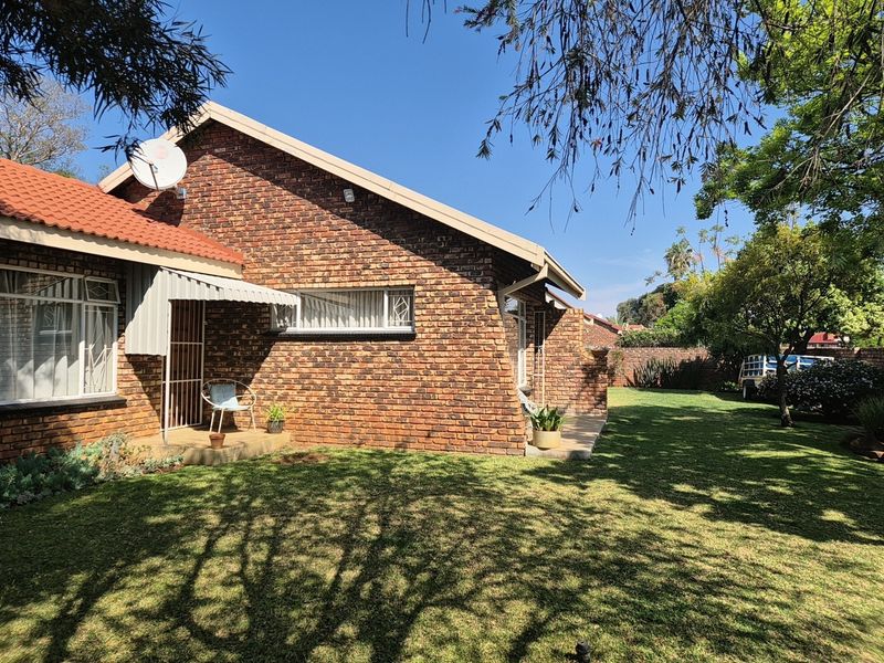 A view of the rear exterior of the house featuring a face brick facade, tiled roof, and a well-maintained garden area.
