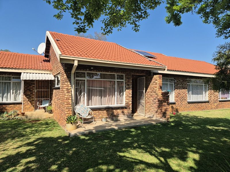 A well-maintained single-story face brick house featuring a terracotta tiled roof, solar panels, and a covered front patio area.