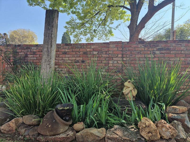 A landscaped garden area featuring a rustic brick boundary wall and a rockery with established greenery.