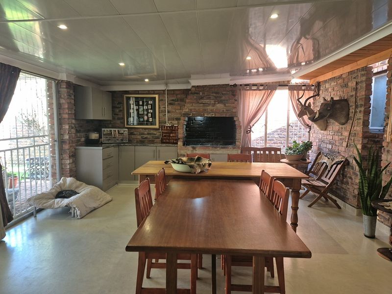 Enclosed patio area featuring exposed brick walls, a built-in braai, recessed ceiling lighting, and sliding glass doors leading to the garden.