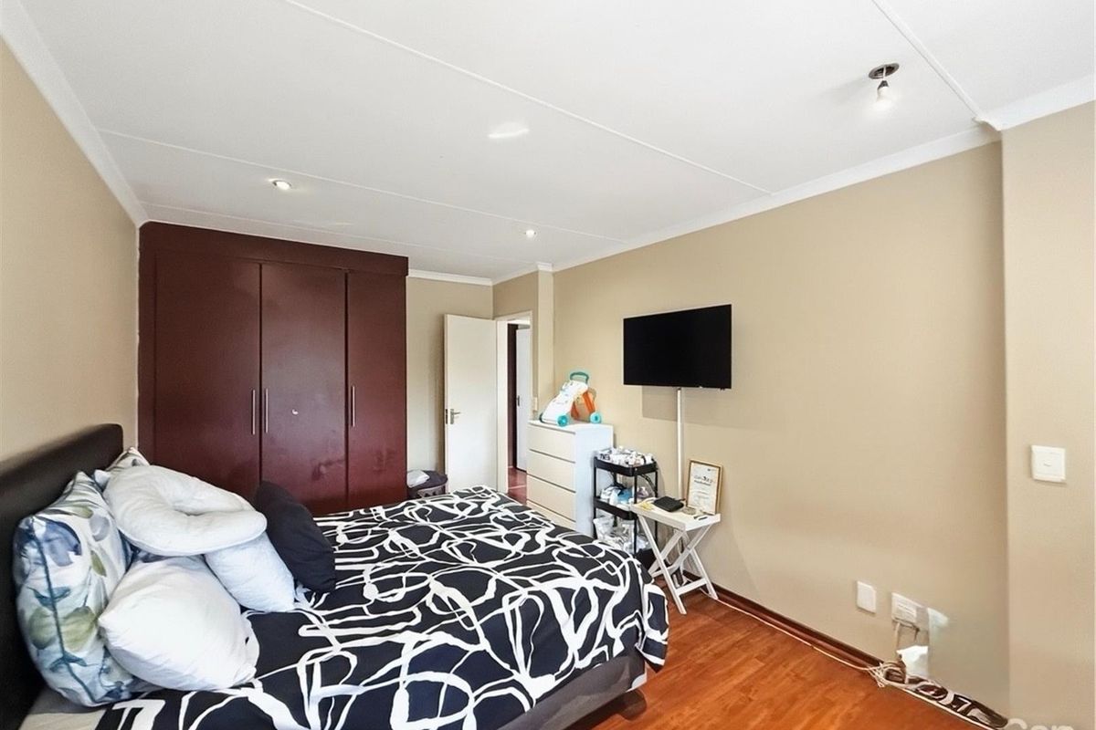 A well-proportioned bedroom featuring laminate flooring, built-in cupboards, and recessed ceiling lighting.