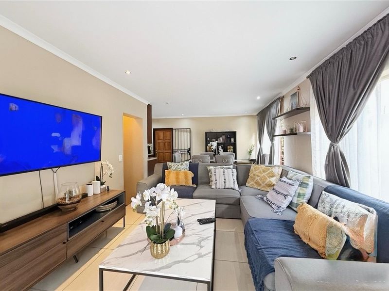 Spacious open-plan living area featuring neutral tiled flooring, recessed downlighting, and coved cornicing, creating a bright and well-maintained communal space.
