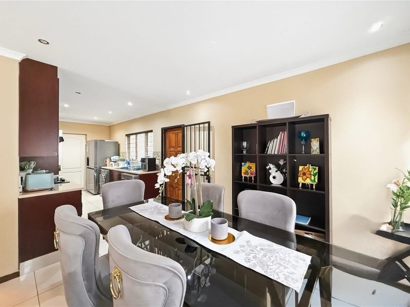 Open-plan dining and kitchen area featuring tiled flooring, recessed lighting, and dark-toned cabinetry, providing a functional and connected living space.