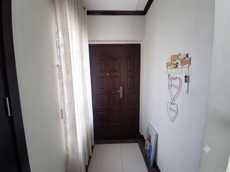 A functional entrance area featuring a solid wood panel door, tiled flooring, and neutral wall finishes.